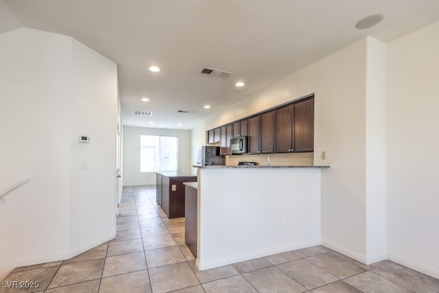 4542 Townwall St, Las Vegas, NV 89115 - kitchen featuring black appliances, dark brown cabinets, dark stone countertops, and visible vents