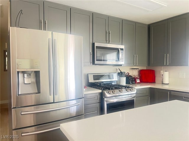 kitchen featuring gray cabinets, stainless steel appliances, light countertops, and wood finished floors