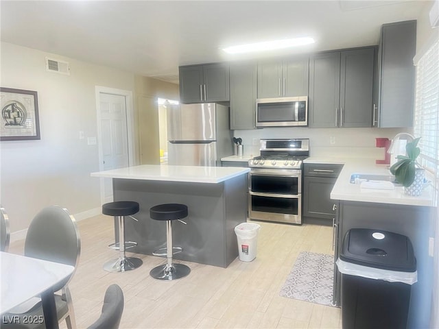 4194 Greenpoint St, Las Vegas, NV 89147 - kitchen with appliances with stainless steel finishes, light countertops, light wood finished floors, a breakfast bar area, and a kitchen island