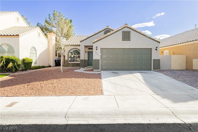 mediterranean / spanish home with a garage, concrete driveway, a tiled roof, and stucco siding