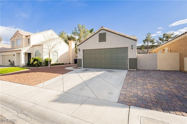 view of front of property featuring concrete driveway, fence, a tiled roof, and stucco siding