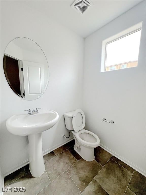 half bath with baseboards, visible vents, and toilet