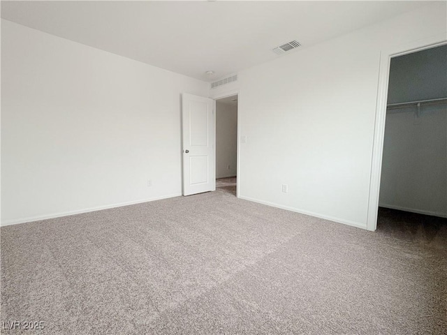 unfurnished bedroom with baseboards, visible vents, a spacious closet, carpet flooring, and a closet