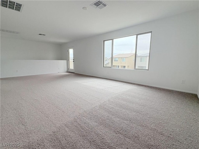 empty room featuring carpet, visible vents, and baseboards