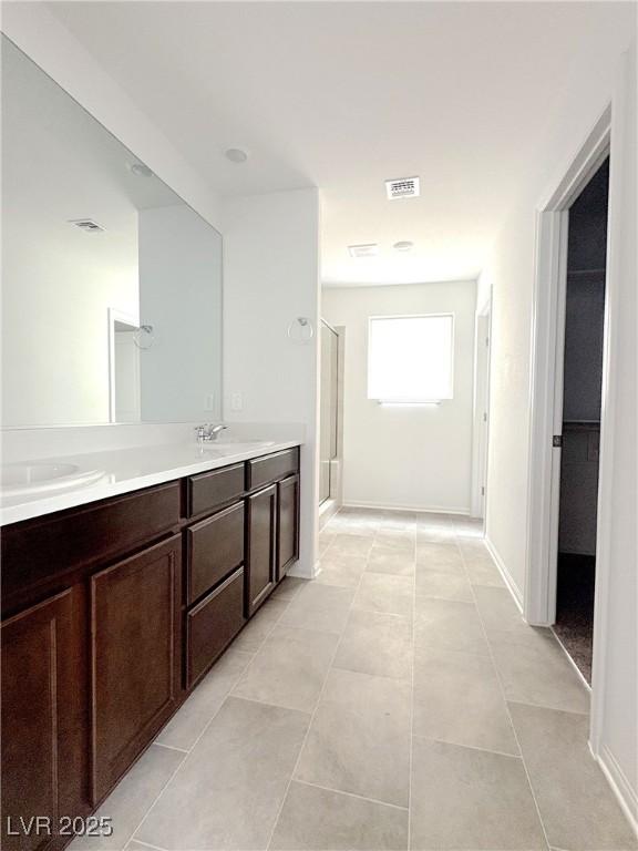 bathroom featuring double vanity, a sink, visible vents, and a shower stall