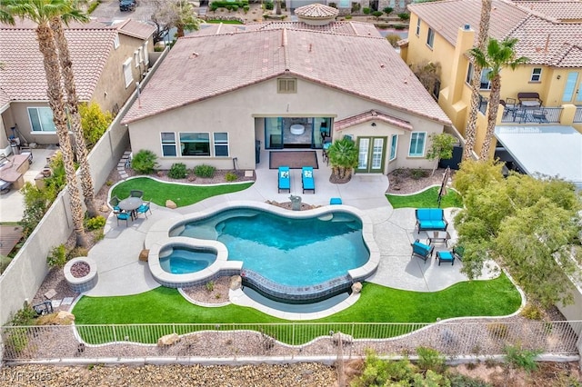 back of property with a fenced backyard, french doors, a patio area, a pool with connected hot tub, and stucco siding