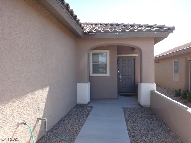 entrance to property featuring a tile roof and stucco siding