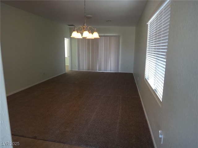 carpeted spare room featuring visible vents, baseboards, and an inviting chandelier