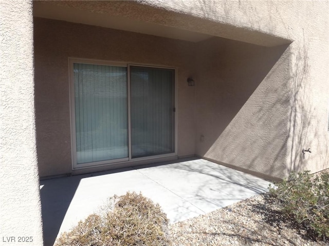 view of exterior entry with a patio area and stucco siding