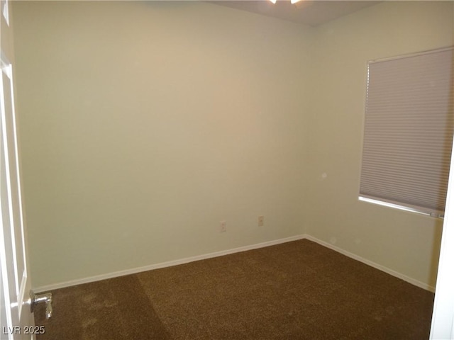 spare room with dark colored carpet and baseboards