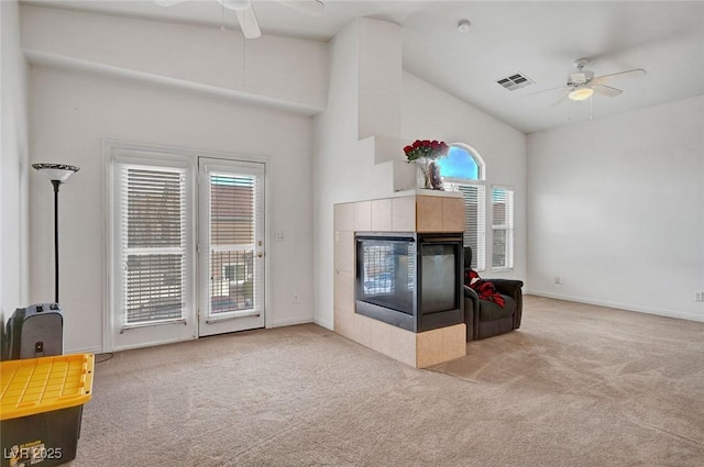 living room featuring a ceiling fan, a tile fireplace, visible vents, and carpet flooring