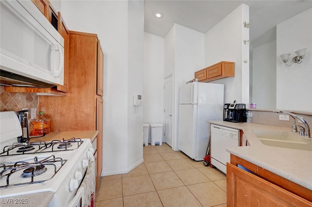 kitchen with white appliances, light tile patterned floors, decorative backsplash, light countertops, and a sink