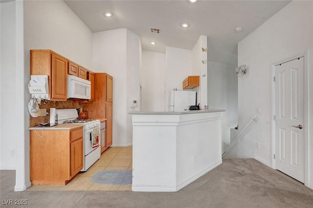 kitchen with light tile patterned floors, recessed lighting, white appliances, visible vents, and light countertops