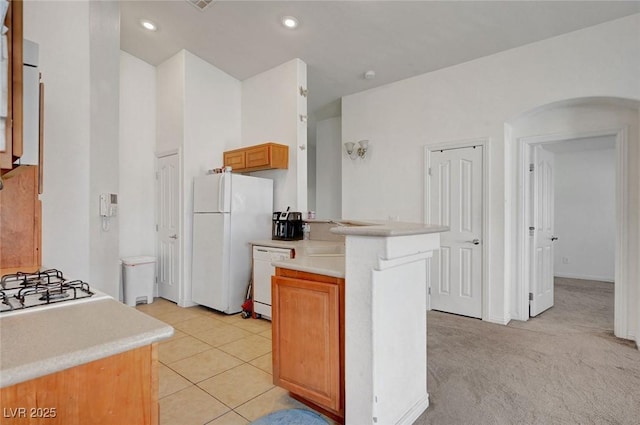 kitchen featuring white appliances, light tile patterned floors, arched walkways, light countertops, and recessed lighting