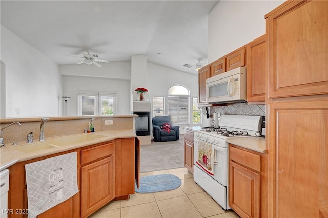 kitchen featuring light tile patterned flooring, white appliances, a sink, a ceiling fan, and backsplash