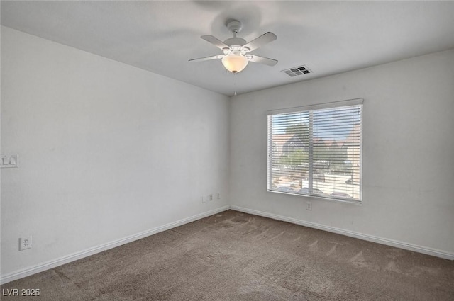 carpeted empty room featuring visible vents, a ceiling fan, and baseboards