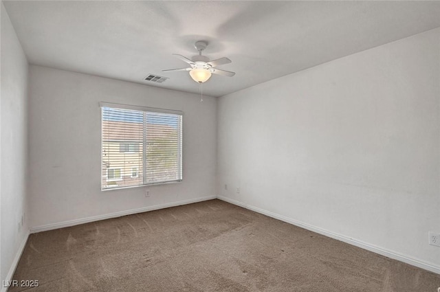 carpeted empty room with baseboards, visible vents, and a ceiling fan