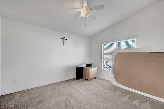 interior space featuring a ceiling fan, lofted ceiling, carpet flooring, and baseboards