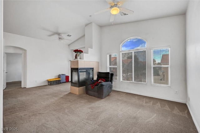 living area with carpet, a fireplace, arched walkways, and ceiling fan