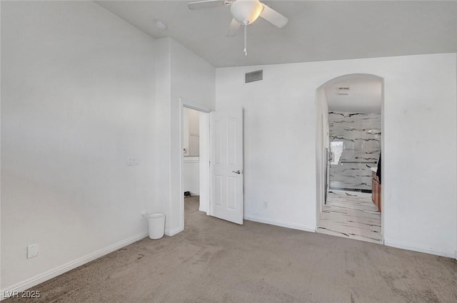 unfurnished bedroom with arched walkways, carpet floors, a ceiling fan, visible vents, and baseboards