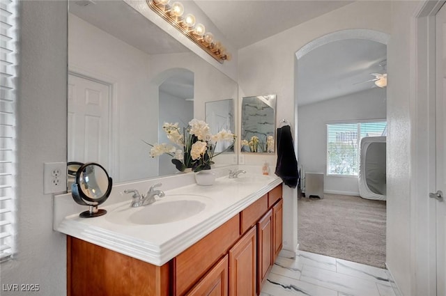 full bathroom with double vanity, ceiling fan, vaulted ceiling, and a sink