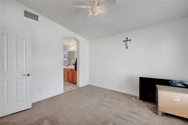 unfurnished bedroom featuring arched walkways, light carpet, visible vents, and baseboards