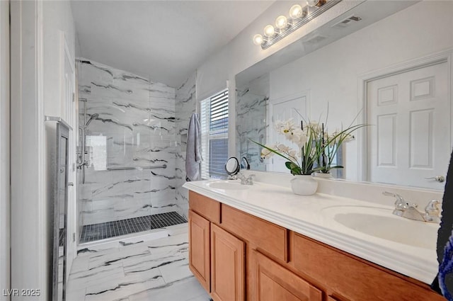 bathroom with double vanity, marble finish floor, a marble finish shower, and a sink