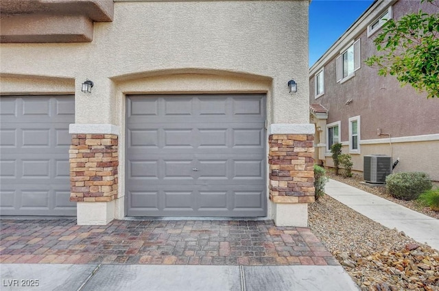 garage featuring decorative driveway and cooling unit