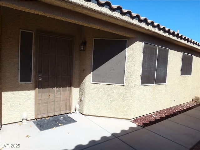 view of side of home with a tile roof and stucco siding