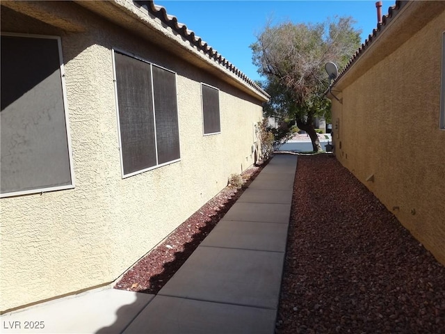 view of side of home with a tiled roof and stucco siding