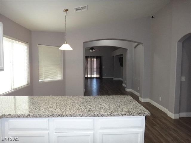 kitchen featuring arched walkways, dark wood finished floors, visible vents, white cabinets, and baseboards