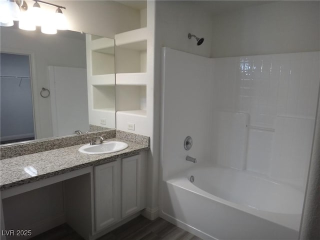 bathroom with shower / bathtub combination, wood finished floors, vanity, and a walk in closet