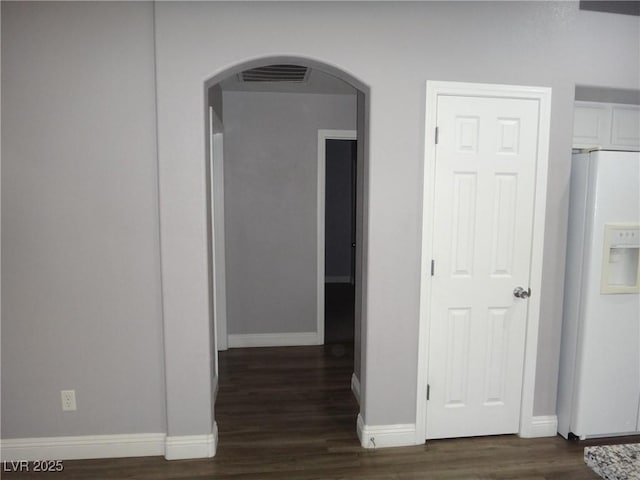 hallway featuring baseboards, visible vents, arched walkways, and wood finished floors