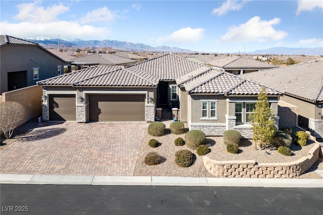 view of front of house featuring decorative driveway, stone siding, a tiled roof, and stucco siding