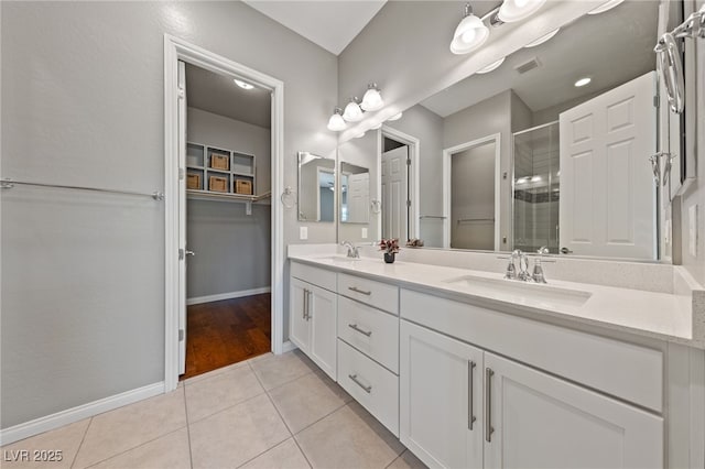 bathroom featuring tile patterned floors, a sink, visible vents, and a shower stall