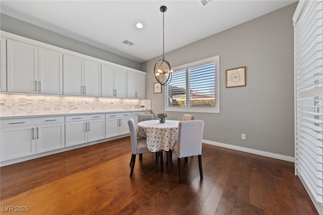 dining room with dark wood-style flooring, visible vents, baseboards, and an inviting chandelier