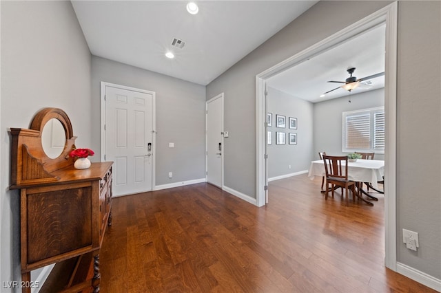 foyer with dark wood-style floors, ceiling fan, visible vents, and baseboards