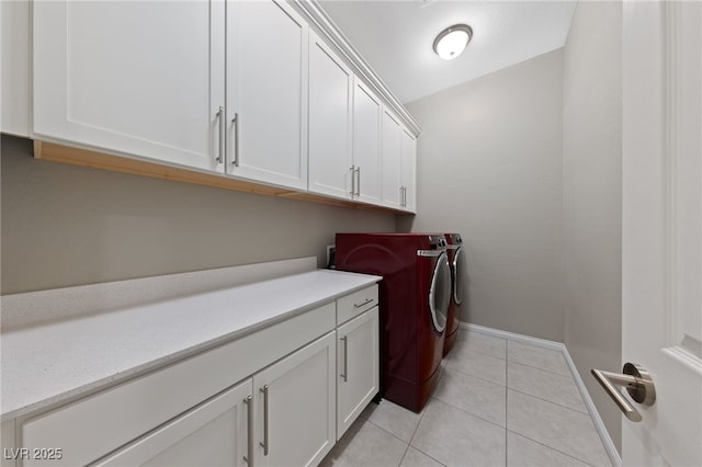 clothes washing area featuring washing machine and dryer, cabinet space, baseboards, and light tile patterned floors