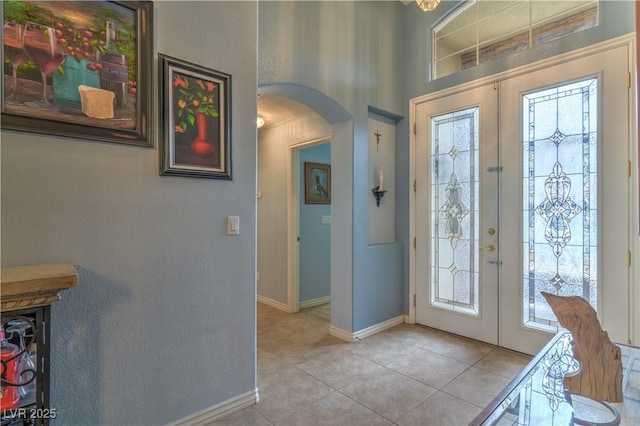 entrance foyer with light tile patterned floors, french doors, arched walkways, and a wealth of natural light