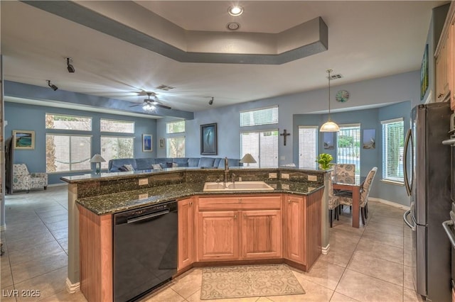 kitchen with open floor plan, dishwasher, dark stone countertops, freestanding refrigerator, and a sink