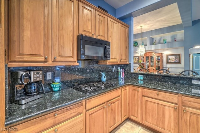 kitchen featuring dark stone counters, black microwave, and gas stovetop