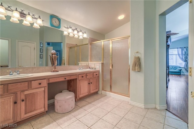 bathroom featuring double vanity, a shower stall, lofted ceiling, and a sink