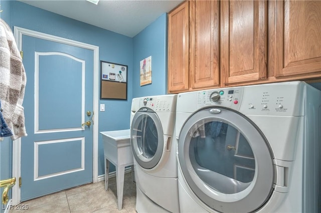 clothes washing area with light tile patterned floors, cabinet space, and washing machine and clothes dryer