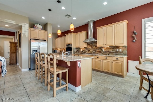 kitchen with decorative backsplash, visible vents, light stone countertops, appliances with stainless steel finishes, and wall chimney range hood