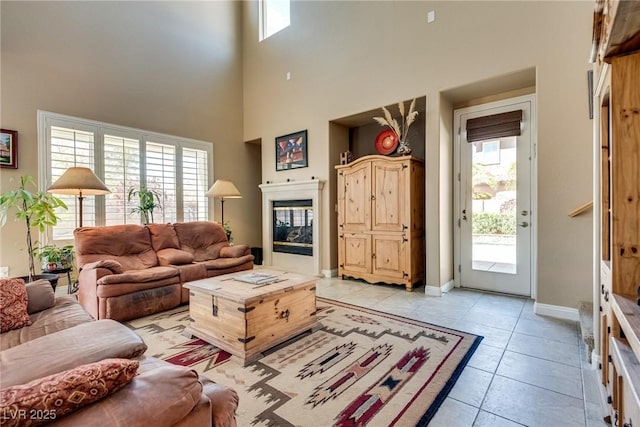 living room featuring light tile patterned flooring, a wealth of natural light, and a glass covered fireplace