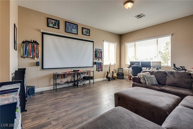 home theater room featuring baseboards, visible vents, and wood finished floors