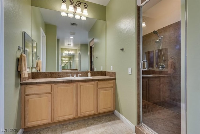 bathroom featuring vanity, baseboards, visible vents, and a shower stall