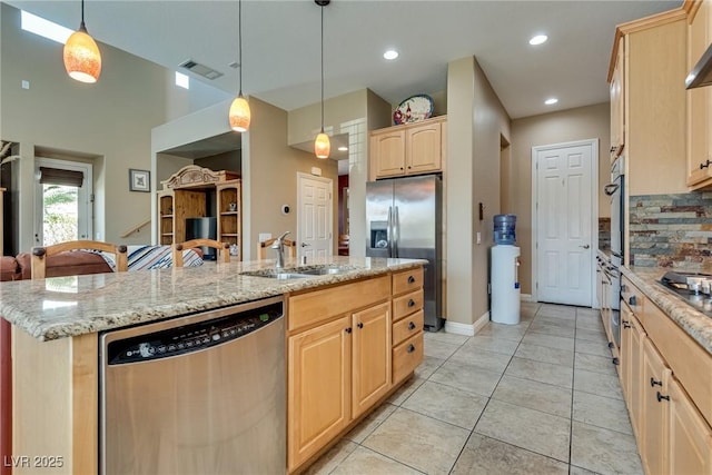 kitchen with a sink, a center island with sink, stainless steel appliances, light brown cabinets, and visible vents