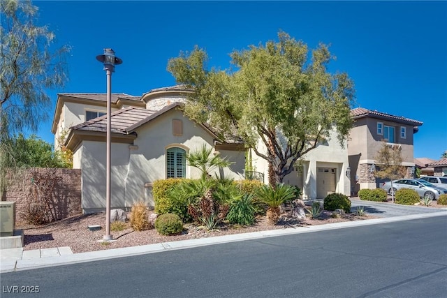 mediterranean / spanish house featuring stucco siding, a tile roof, and concrete driveway