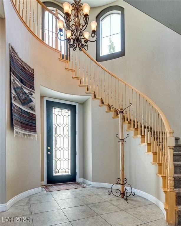 foyer featuring stairs, a high ceiling, baseboards, and an inviting chandelier